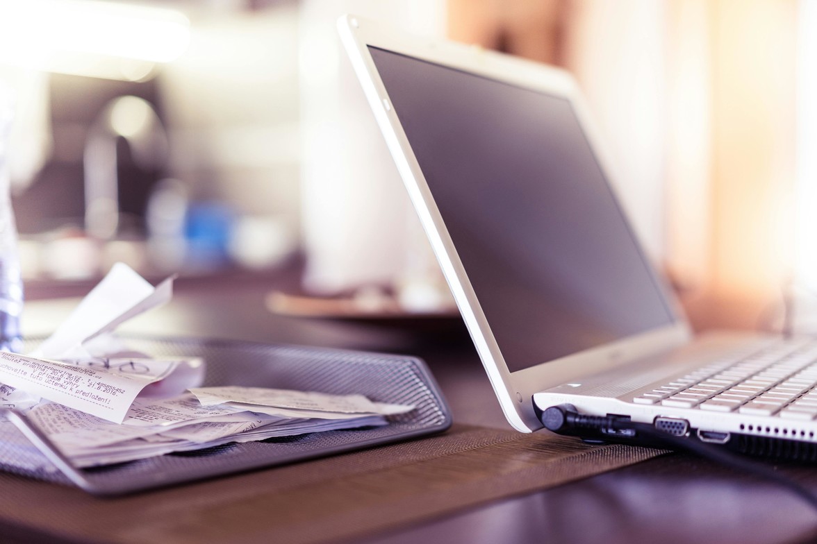A therapist's desk with a stack of receipts next to a laptop.