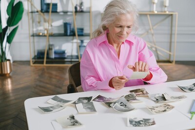 Woman looking at old photographs, symbolizing reflection on personal history and unconscious patterns explored in psychodynamic therapy.