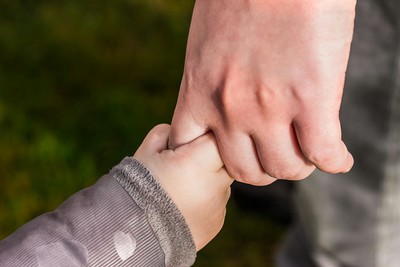 Close-up of a parent holding a child’s hand, symbolizing early emotional bonds and the foundation of attachment-based therapy.