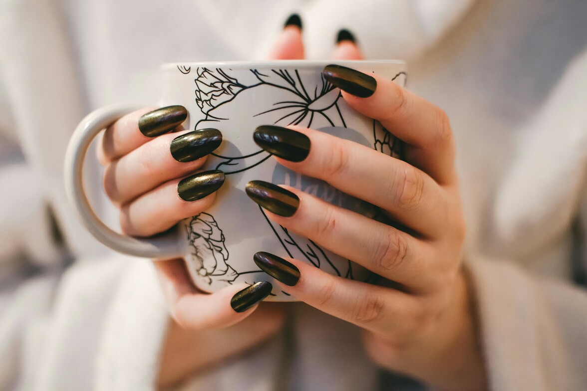 Woman holding warm coffee cup with floral design, taking a quiet moment to slow down and care for her mental health
